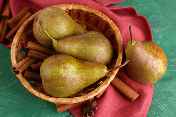 Ripe pears and cinnamon sticks in wicker basket,