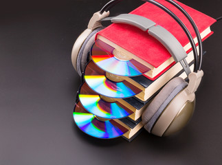 Cd sticks out from red books with headphones on it