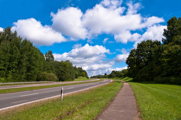 Country Road up the Hill with Trees Around and Cloudy Sky