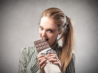 beautiful woman is eating a chocolate bar