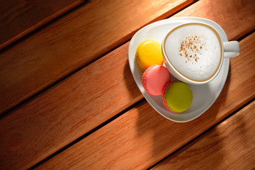 A cup of cappuccino and pastries(macaron) on old wooden table