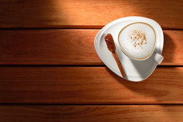 A cup of cappuccino and cinnamon on old wooden background