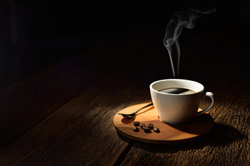Cup of coffee with smoke and coffee beans on wooden background