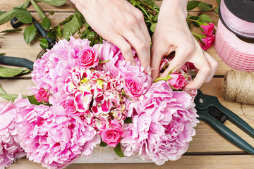Florist at work: woman making floral decoration of pink peonies