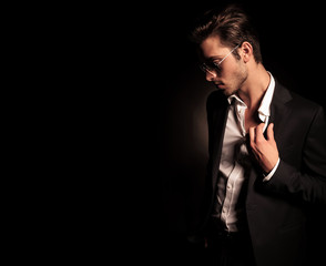 cool fashion man in suit and sunglasses pulling his collar