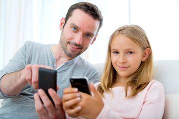 Fototapeta premium Father and his blond daughter using mobile