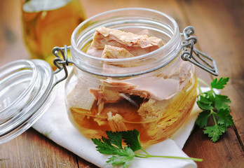 Tuna with parsley  in a glass jar on wooden table