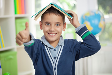 funny schoolboy with a book on head