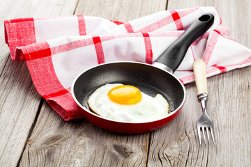 Fried egg in a frying pan, on an old wooden table