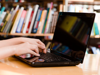 closeup hands typing on notebook in library