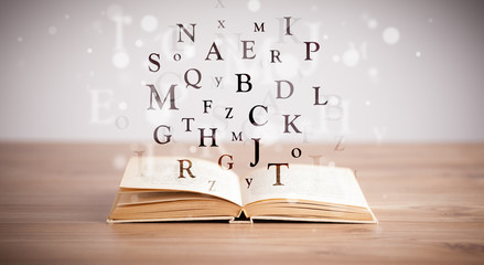 Opened book with flying letters