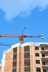 Crane and building construction site against blue sky