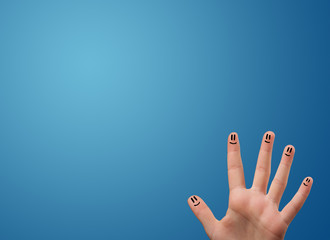 Happy smiley face fingers looking at empty blue background copy