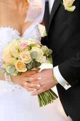 Young couple with a bouquet of flowers and rings after the weddi