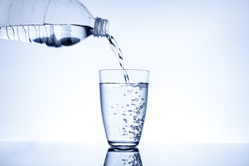 Water flowing from a plastic bottle into a glass