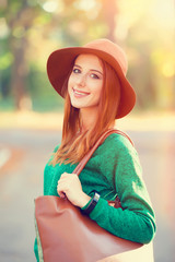 Redhead girl in hat in the autumn park.