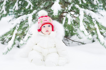 Adorable little baby playing in snow in a winter park