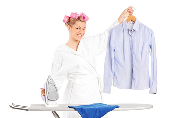 Woman standing behind an ironing board and holding a shirt