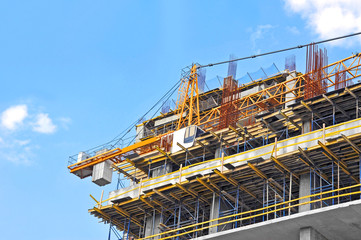 Crane and building construction site against blue sky