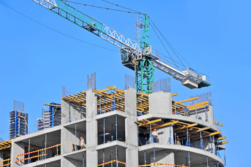 Crane and building construction site against blue sky