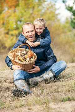 Happy smiling son and father with full basket of mashrooms