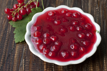 Red currant jam in a white platter and a sprig of currant with b