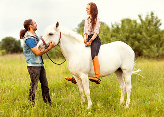Young beautiful couple with a horse at sunset.