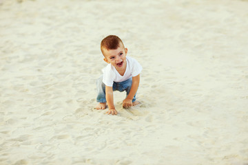boy laughing in the sand, walking along the beach