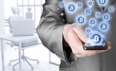 Hand with mobile smart phone and bitcoin symbol