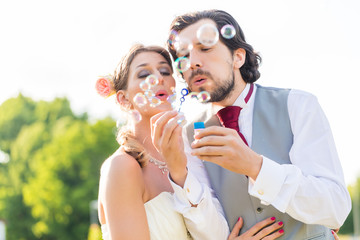 Hochzeitspaar pustet Seifenblasen auf Feld