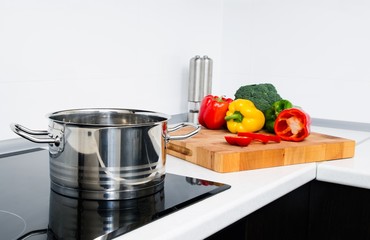 Pot and vegetables in modern kitchen with induction stove - obrazy, fototapety, plakaty