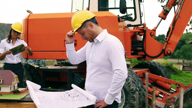 Worried engineer looking on the project and woman using tablet