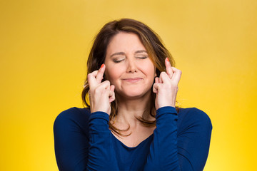 Woman, mother crossing her fingers on yellow background 