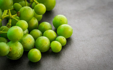 Unripe green grapes on dark background. Selective focus.