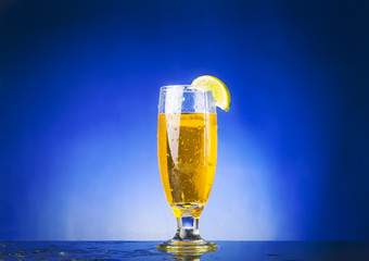 glass withe yellow liquid on blue background