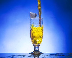 splash glass withe yellow liquid on blue background