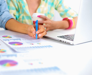 Two women working together at office, sitting on the desk