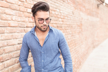 young casual man with glasses looks down