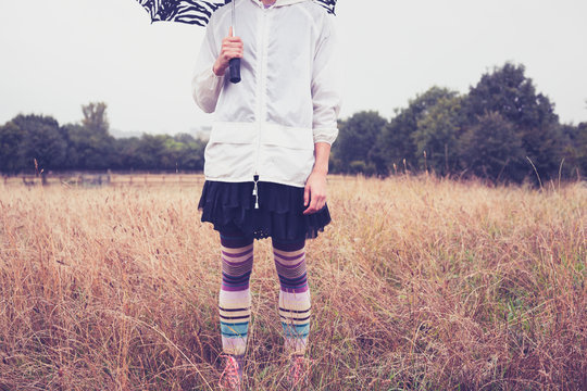 Young woman with umbrella standing in field