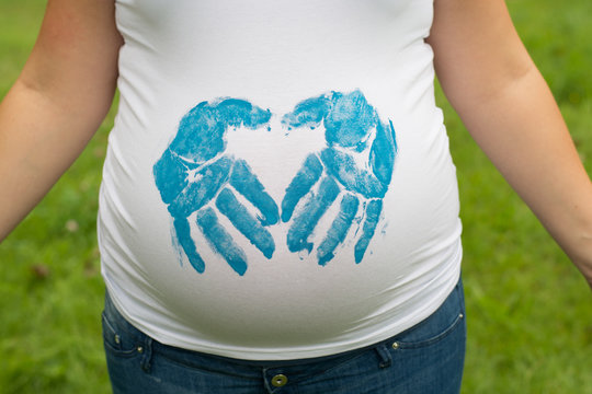 Pregnant Woman making handprint in heart shape 