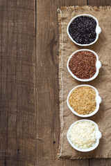 Variety of rice in bowls on wooden table