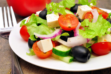 Greek salad and fork on a wooden table