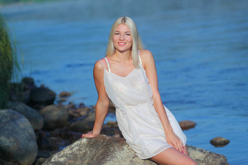 Romantic sweet girl sitting on a rock by the sea 