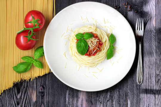Spaghetti on white plate with pasta and tomatoes