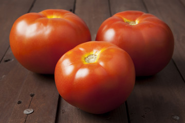 Three tomatoes on brown table