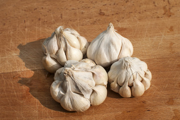 Four garlic cloves on wooden board background