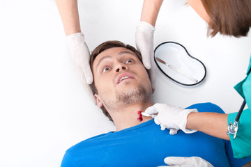 young man lying on floor with blood on neck.