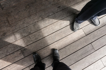 Shoes of two employee standing on Plank