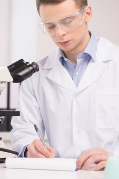 Confident clinician studying chemical elements in laboratory.