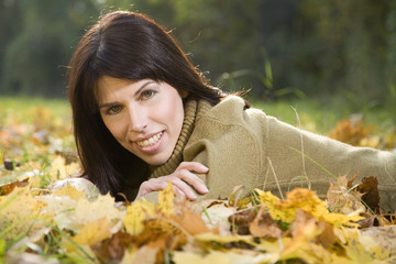 Brunette Frau entspannt auf Herbstlaub , Portrait